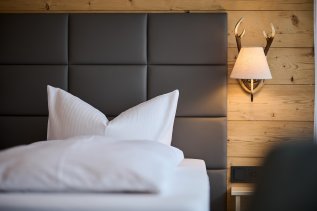Einblick in ein Zimmer im Hotel Bannwaldsee in Halblech mit Blick auf das Doppelbett