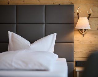 Einblick in ein Zimmer im Hotel Bannwaldsee in Halblech mit Blick auf das Doppelbett