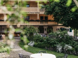 Außenansicht vom Das Naturhotel Chesa Valisa in Hirschegg / Kleinwalsertal im Sommer mit Blick auf einen Tisch im Garten