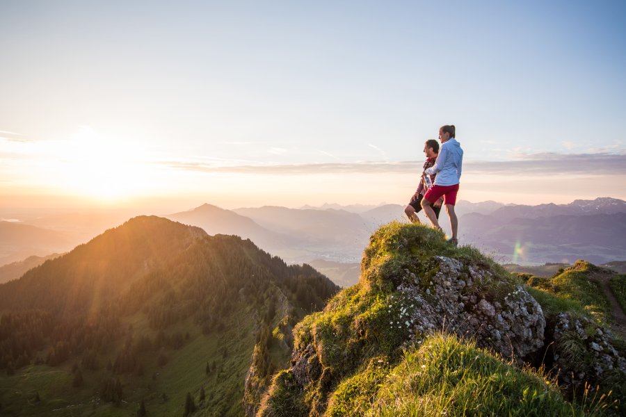 Allgäuer Alpenwasser Wandern Zwei Personen stehen auf einer Anhöhe beim Wandern und blicken in die Ferne