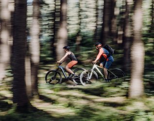 Ein Paar machte ine Fahrradtour durch den Wald beim Hotel Torgheles Wald und Fluh in Balderschwang.