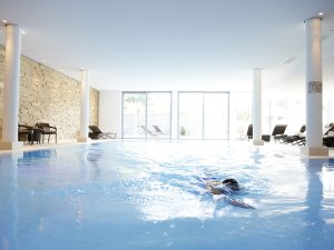 Eine Person schwimmt im Innenpool des Hotel Exquisits in Oberstdorf