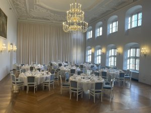 Festsaal im Kloster Irsee in Irsee mit hohen Decken und einem feierlichen Kronleuchter sowie Tischreihen im Kreis