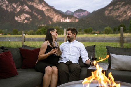 Ein Paar sitz am Lagerfeuer draußen am Hotel Das Rübezahl in Schwangau.