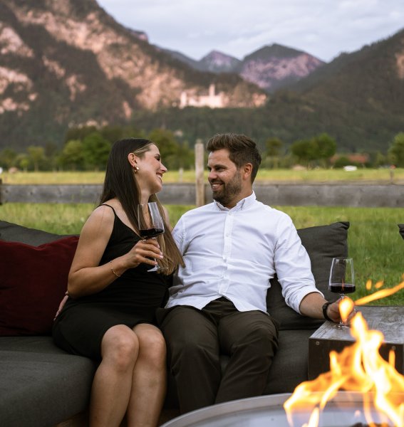 Ein Paar sitz am Lagerfeuer draußen am Hotel Das Rübezahl in Schwangau.