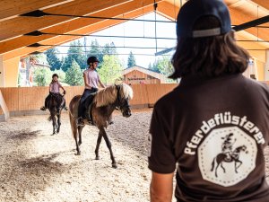 Zwei Kinder reiten in der Reithalle des Allgäuer Berghofs in Gunzesried.