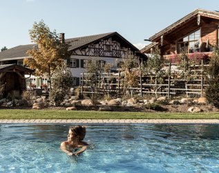 Eine Frau schwimmt im Sommer im Pool der Alpzitt Chalets in Burgberg.