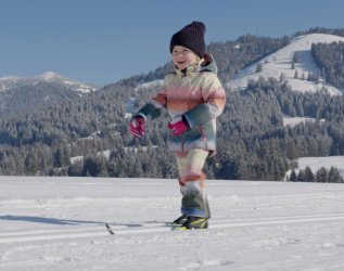 Ein Kind auf Langlauf Skiern im Winter nahe des Torgheles Wald und Fluh in Balderschwang.