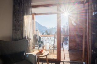 Ein Zimmer mit Balkon und mit winterlicher Aussicht auf Oberstdorf im Hotel Exquisit in Oberstdorf.
