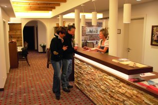 Ein Paar checkt bei einer Mitarbeiterin der Rezeption im Hotel Garni Schellenberg in Oberstdorf ein