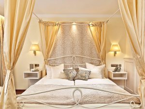 Einblick in eines der modernen Zimmer mit Himmelbett im Hotel Schlosskrone in Füssen
