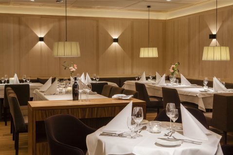 Einblick in den Speiseraum des Hotel Allgäu Sonne in Oberstaufen mit eingedeckten Tischen und stimmungsvoller Beleuchtung