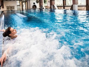 Eine Frau, die Gast im Hotel Prinz-Luitpold-Bad in Bad Hindelang ist, entspannt sich im Innenpool mit Massagedüsen.