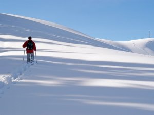 Ein Gast macht eine Wanderung auf einen Berg im Winter in der Nähe des Naturlandhauses Krone in Maierhoefen.