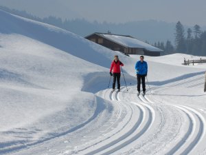 Ein Paar geht gemeinsam Langlaufen auf einer Loipe in der Nähe des Naturlandhauses Krone in Maierhoefen.