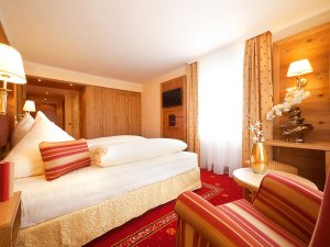 Einblick in eines der gemütlich eingerichteten Zimmer mit roten Details und Doppelbett im Hotel Schlosskrone in Füssen