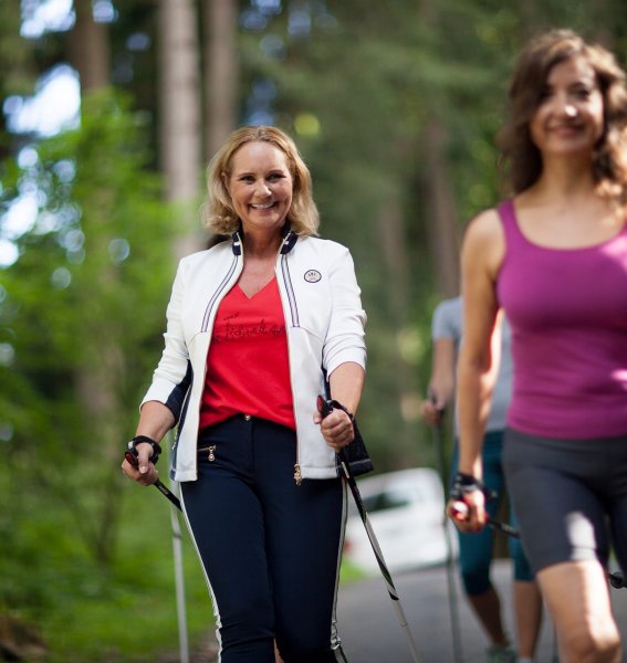 Eine Gruppe von Gästen unternimmt eine Nordic Walking Tour durch einen Wald in der Umgebung des Rosenalp Gesundheitsresorts und Spa in Oberstaufen