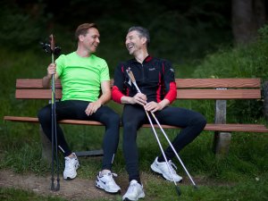 Zwei Gäste machen eine Pause auf einer Bank bei einer Wanderung durch einen Wald in der Umgebung des Rosenalp Gesundheitsresorts und Spa in Oberstaufen