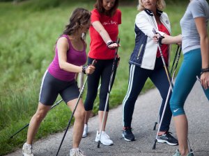 Eine Gruppe von Gästen macht eine Nordic Walking Tour mit Dehnübungen in der Umgebung des Rosenalp Gesundheitsresorts und Spa in Oberstaufen