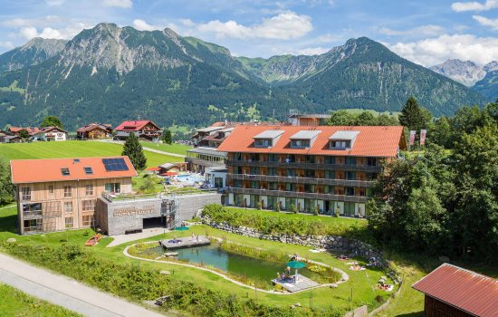Außenansicht des Hotel Oberstdorf in Oberstdorf mit Blick auf die Hotelgebäude und den Schwimmteich im Sommer