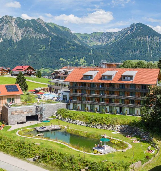 Außenansicht des Hotel Oberstdorf in Oberstdorf mit Blick auf die Hotelgebäude und den Schwimmteich im Sommer