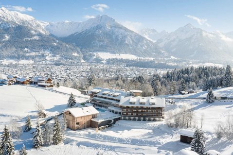 Außenansicht des Hotel Oberstdorf in Oberstdorf im Winter mit Blick auf die Hotelgebäude und den schneebedeckten Schwimmteich