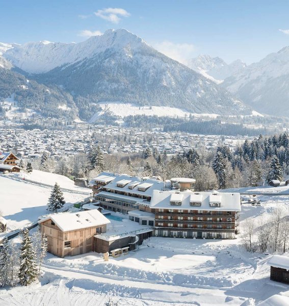 Außenansicht des Hotel Oberstdorf in Oberstdorf im Winter mit Blick auf die Hotelgebäude und den schneebedeckten Schwimmteich