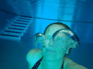 Eine Frau taucht im Pool und macht Blasen unter Wasser im Rosenalp Gesundheitsresort und Spa in Oberstaufen