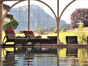 Eindruck vom Innenpool mit großen Panoramafenstern und Blick auf die Berge im Schüle's Gesundheitsresort und SPA in Oberstdorf