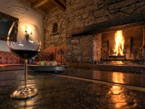 Ein Glas Rotwein am Kamin im Wellnesshotel Mittelburg in Oy-Mittelberg genießen.