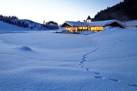 Die Außenansicht des beleuchteten Haubers Naturresorts in Oberstaufen im Winter.