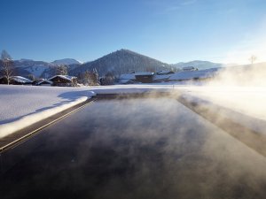 Der Außenpool mit Bergpanorama im Winter im Haubers Naturresort in Oberstaufen.