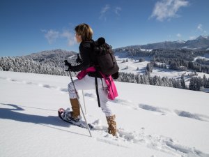 Eine Frau, die Gast im Haubers Naturresort in Oberstaufen ist, macht eine Wanderung durch die Winterlandschaft.