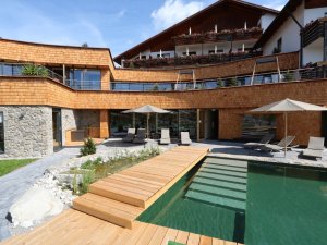 Die Außenansicht des Biohotels Eggensberger in Füssen / Hopfen am See mit Außenpool im Sommer.