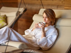 Eine Frau genießt eine Auszeit auf einer Ruheliege im Wellnessbereich des Biohotel Eggensberger in Füssen / Hopfen am See