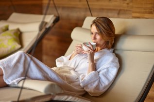 Eine Frau genießt eine Auszeit auf einer Ruheliege im Wellnessbereich des Biohotel Eggensberger in Füssen / Hopfen am See