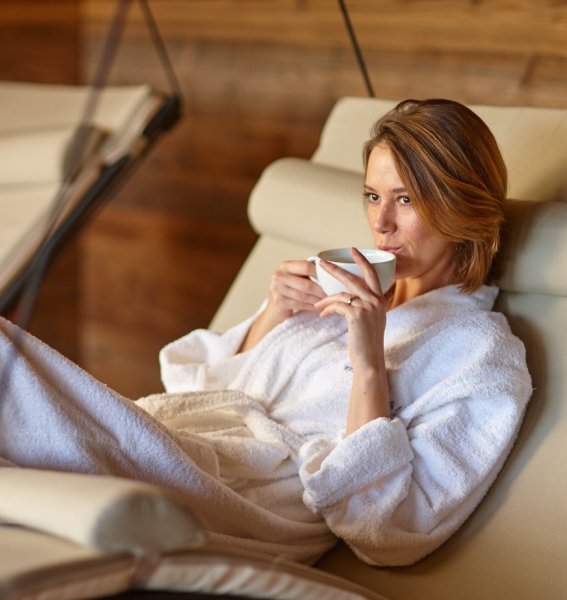 Eine Frau genießt eine Auszeit auf einer Ruheliege im Wellnessbereich des Biohotel Eggensberger in Füssen / Hopfen am See