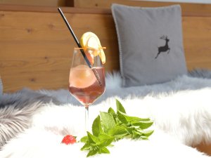 Sitzgelegenheit im Freien mit dekorativen Fellen und einem Erfrischungsgetränk im Landhotel Alphorn in Ofterschwang