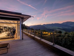 Außenansicht vom Hotel Allgäu Sonne in Oberstaufen an einem Sommerabend mit Blick auf den Fitnessraum und die umliegende Landschaft