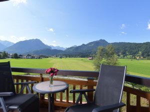 Ein Balkon mit Tisch und Stühlen lädt zum Entspannen im Hotel Alpenhof in Oberstdorf vor Bergpanorama im Sommer ein