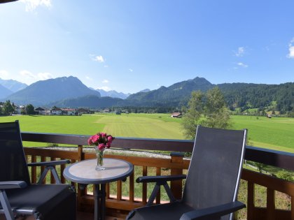 Ein Balkon mit Tisch und Stühlen lädt zum Entspannen im Hotel Alpenhof in Oberstdorf vor Bergpanorama im Sommer ein