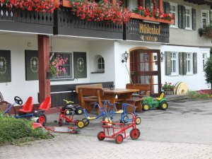 Die Außenansicht des Hotelgebäudes des Hotels Mühlenhof in Oberstdorf im Sommer mit Spielgeräten für Kinder