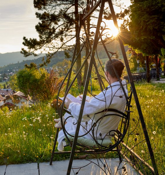 Eine Frau genießt eine Auszeit in der Eisenschaukel im Außenbereich des Hotel Prinz-Luitpold-Bads in Bad Hindelang
