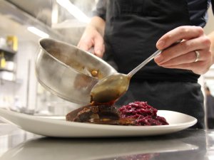 Ein Mitarbeiter der Küche im Hotel Mohren in Oberstdorf  bereitet eine Speise ansprechend zu