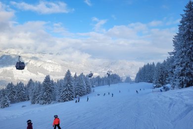 Weite Skipiste unter blauem Himmel mit Blick auf die verschneiten Allgäuer Alpen.