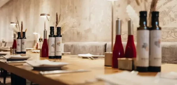 In einem Restaurant sind Tische mit Dekoration und Geschirr für Gäste vorbereitet. Es ist hell und einladend.