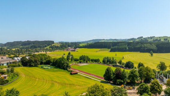 Weite Felder und Bäume prägen die Aussicht auf das Dorf an einem sonnigen Tag im Frühling.