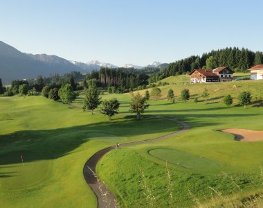 Golfspieler genießen unter blauem Himmel die malerische Landschaft mit Bergen und Wiesen während eines schönen Tages.