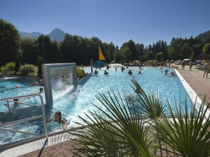 Viele Gäste entspannen und schwimmen in einem attraktiven Freizeitbad an einem sonnigen Sommertag.