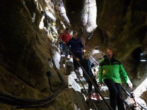 Eine Gruppe von Menschen wandert auf einer Treppe durch eine beeindruckende Höhlenlandschaft in Deutschland.